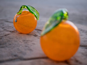 two blown glass ornamentss orange with green leaf